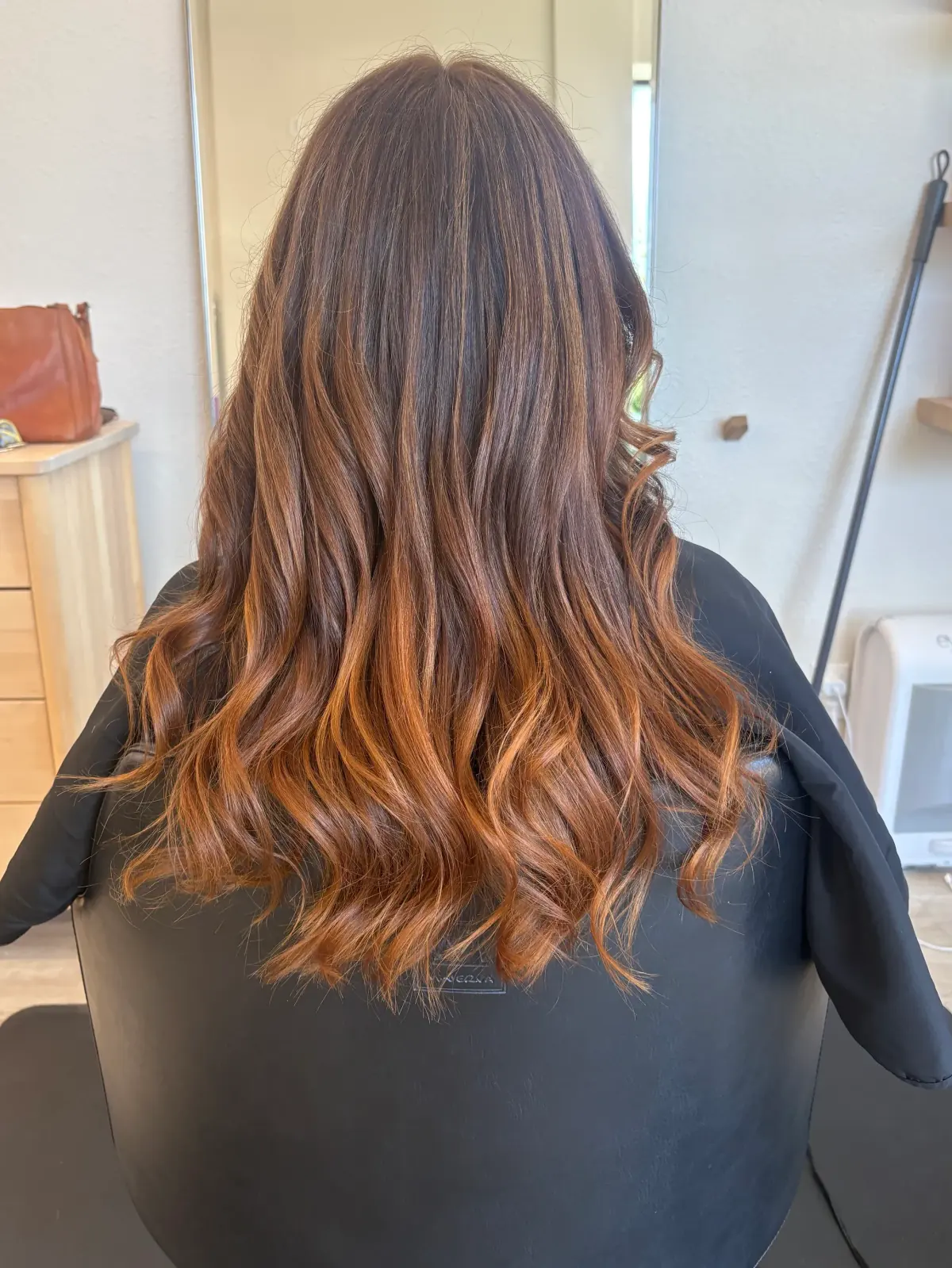 Brunette hair with copper and caramel highlights in loose waves.