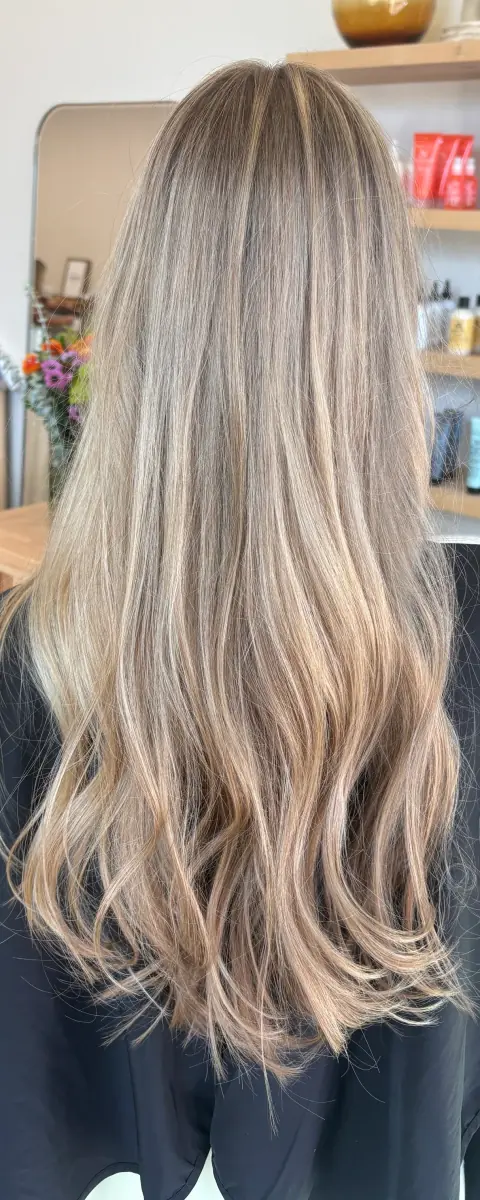 Long beige-blonde hair with soft waves and a natural root blend.
