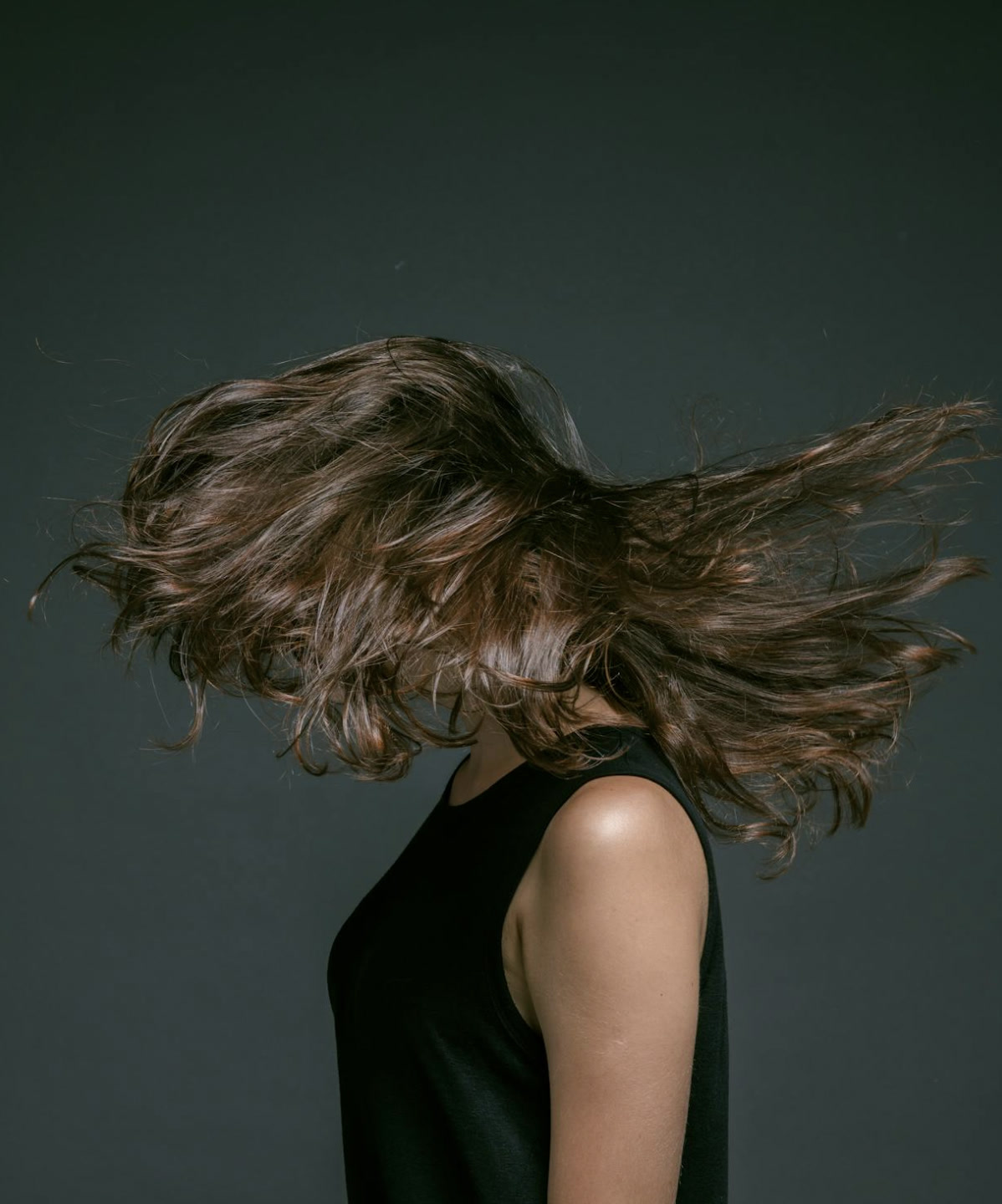 Brunette hair styled in motion against a dark studio backdrop