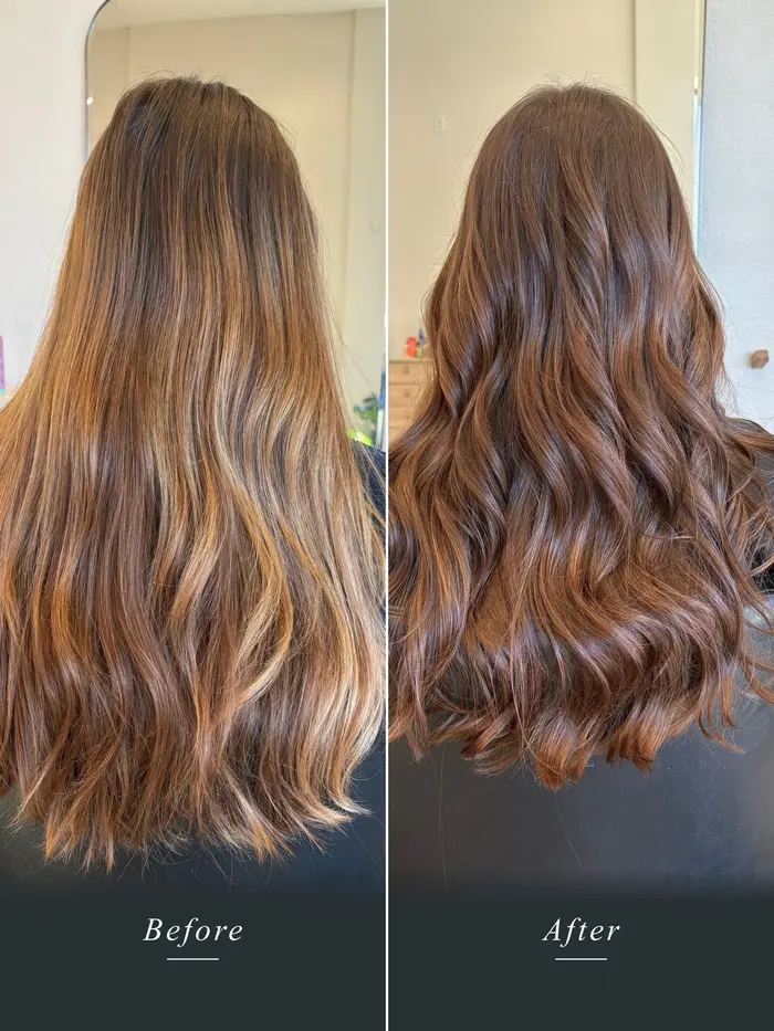 Before and after: long hair with uneven, brassy orange ends corrected to a warm, even chestnut brunette with soft waves.